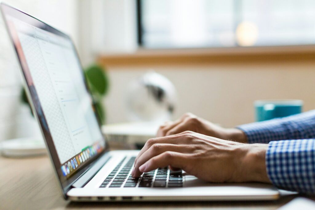 Person typing on a silver MacBook, making updates to a website