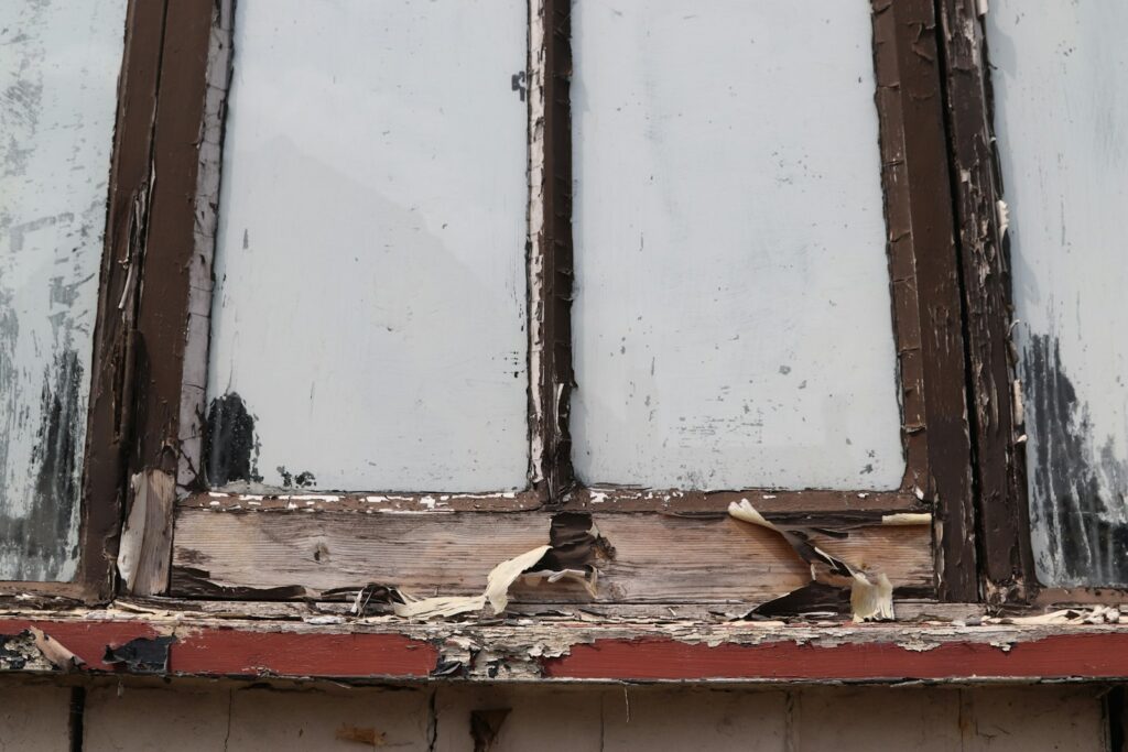 Damaged window frame with peeling paint, the kind of fault worth noting before a repair visit